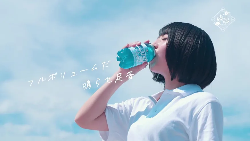 青空の下で飲み物を口にする少女