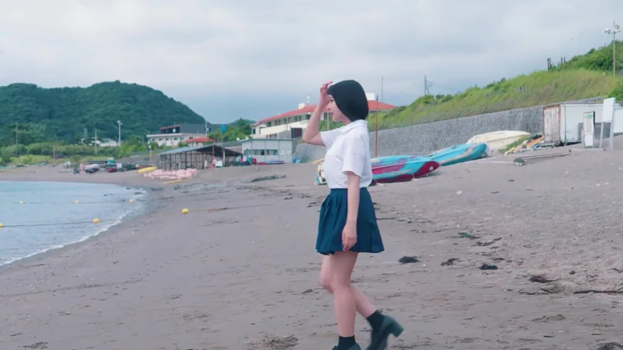 海岸沿いを歩く制服姿の少女
